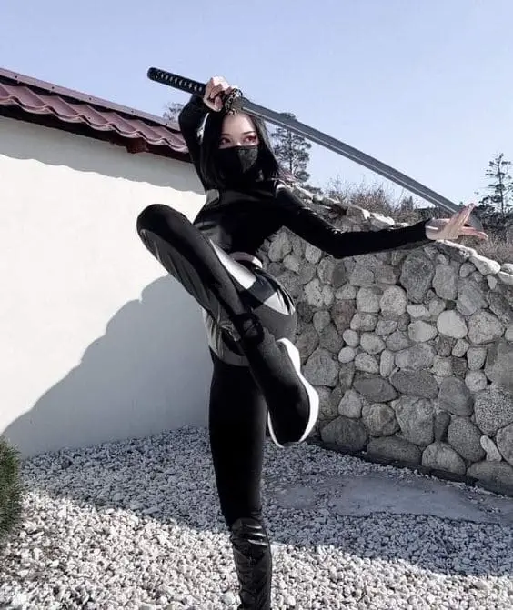 female posing with one leg up ready to kick while holding the katana