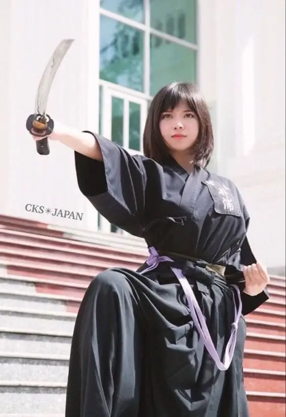 female warrior pointing katana pose with one leg up
