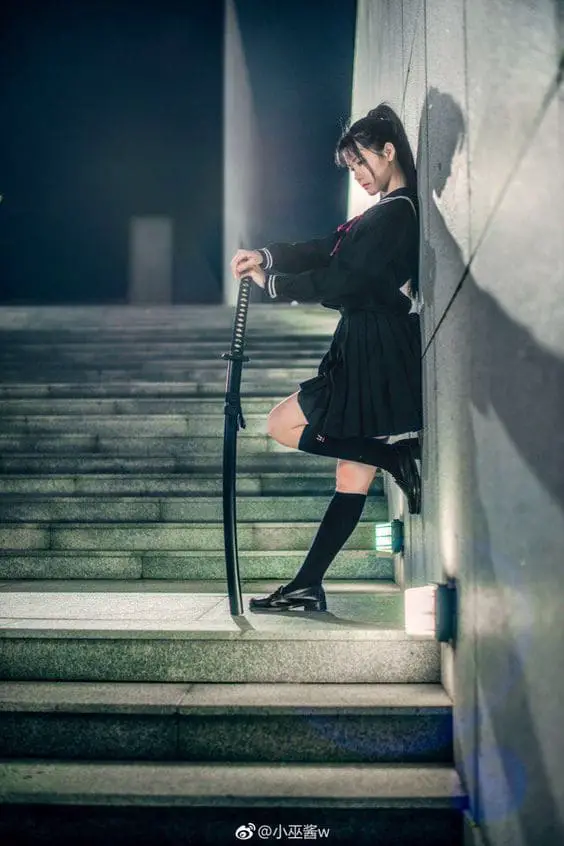 girl leaning on wall while posing with katana sword