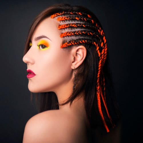 side view of a lady with sharp side head orange braids
